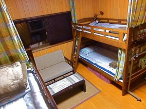Aoshima Guesthouse Hooju في ميازاكي: غرفة بها ثلاثة أسرة بطابقين وأريكة