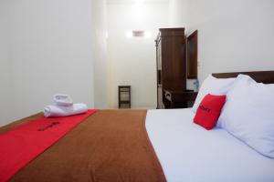 1 dormitorio con 1 cama grande con almohadas rojas y blancas en Reddoorz at Bale Eja Syariah Senggigi en Montongbuwoh