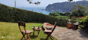 2 sillas y una mesa en un patio con vistas al océano en CASA RURAL ABLANO CUDILLERO en PLAYA CONCHA ARTEDO, en Lamuño