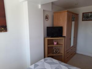 a bedroom with a bed and a cabinet with a television at Private Guest Suite in Telscombe