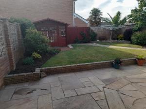 a backyard with a brick retaining wall and a lawn at Private Guest Suite in Telscombe