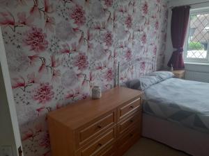 a bedroom with a bed and floral wallpaper at Private Guest Suite in Telscombe
