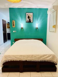 een slaapkamer met een bed met een groene muur bij Studio avec vue sur la mer piscine partagee et terrasse amenagee a Le Marin a 3 km de la plage in Le Marin