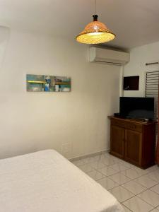 een slaapkamer met een bed en een televisie en een lamp bij Studio avec vue sur la mer piscine partagee et terrasse amenagee a Le Marin a 3 km de la plage in Le Marin