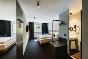 a hotel room with two beds and a bathroom at NIGHT INN Hotel Bahnhofcity Feldkirch in Feldkirch