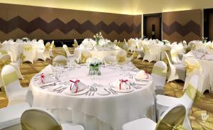 d'primahotel Tangerang في تانغيرانغ: قاعة احتفالات بطاولات بيضاء وكراسي بيضاء