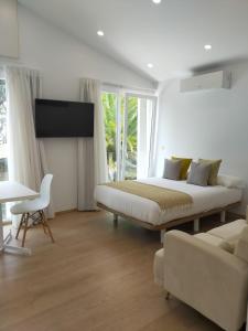 Habitación blanca con cama y sofá en Píllaras da Lanzada en A Lanzada