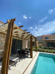een patio met een tafel en een zwembad bij VILLAS BALATSOURAS in Paleros