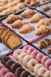 eine Ausstellung verschiedener Arten von Donuts und Gebäck auf Tabletts in der Unterkunft Hotel Monaco & Quisisana in Lido di Jesolo