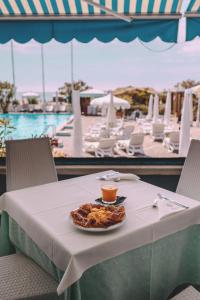ein Teller mit Essen auf einem Tisch mit Pool in der Unterkunft Hotel Monaco & Quisisana in Lido di Jesolo