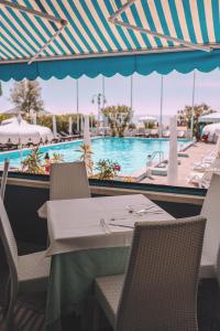 einen Tisch und Stühle in einem Restaurant mit Pool in der Unterkunft Hotel Monaco & Quisisana in Lido di Jesolo