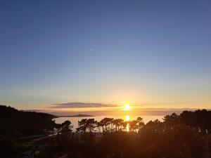 a sunset over a body of water with trees at JALEPA in Muxia