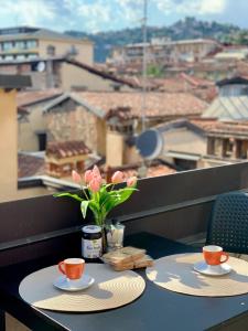 een tafel met twee kopjes en een vaas met bloemen op een balkon bij Magic Place Bergamo! Appartamento Relax con terrazza nel cuore di Bergamo in Bergamo