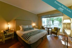 a bedroom with a bed and a table and a window at HR Hôtel-Restaurant & Spa Marin in La Flotte