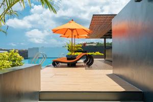 a patio with a table and an umbrella and a bench at Wekata Luxury in Kata Beach