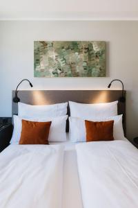 un letto con lenzuola bianche e cuscini arancioni di NIGHT INN Hotel Bahnhofcity Feldkirch a Feldkirch