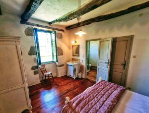 a bedroom with a bed and a table and a window at L'ancienne Forge de Cregols in Crégols