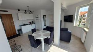 a kitchen and a living room with a table and chairs at Apartamenty Baltic Korona B19 in Darłowo
