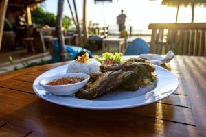 a plate of food with rice and meat on a table at The Pande Hill Homestay in Uluwatu