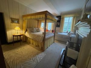 sypialnia z łóżkiem z baldachimem i stołem w obiekcie Barton Hall Country House w mieście Pooley Bridge