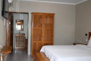 a bedroom with a white bed and a wooden cabinet at Pescador Villas in Inhambane