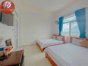 a room with two beds and a desk and a window at Binh Yen Hotel in Ly Son