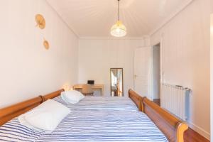 Schlafzimmer mit einem Bett mit blauen und weißen Streifen in der Unterkunft EKI ETXEA Piso en Orio para 6 personas al lado de San Sebastián PARKING in Orio