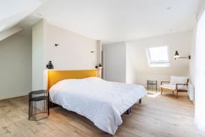 biała sypialnia z dużym łóżkiem i krzesłem w obiekcie Les Peupliers - maison de vacances avec jardin w mieście Bénodet