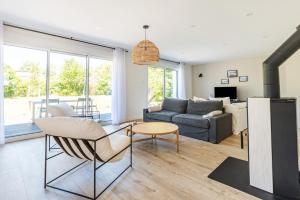 ein Wohnzimmer mit einem Sofa und einem Tisch in der Unterkunft Les Peupliers - maison de vacances avec jardin in Bénodet