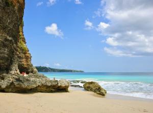 a beach with rocks and the ocean with people on it at Sunset Villa in Jimbaran