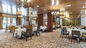 a dining room with tables and chairs and chandeliers at Hotel Jezero in Plitvička Jezera