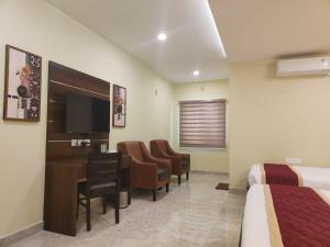 a hotel room with a bed and a desk and chairs at Eshanya Comforts in Attibele