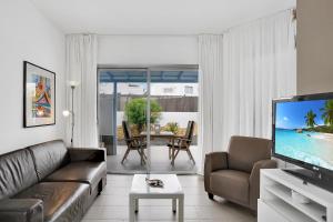 a living room with a couch and a flat screen tv at Mar Azul Corralejo- Adults Only in Corralejo