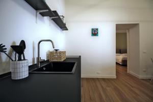 een zwarte keuken met een wastafel en een slaapkamer bij Casa Maggie in LʼAquila