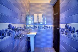 a blue tiled bathroom with a sink and a mirror at Ark of Avalon Near IGI AirPort New Delhi in New Delhi