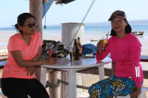 Due donne sedute a un tavolo sulla spiaggia con bevande di Pescador Villas a Inhambane