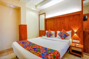 um quarto com uma cama grande e uma cabeceira em madeira em FabExpress Super 7 Inn em Mumbai