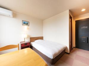 a hotel room with a bed and a table at Tabist Travel Inn Shinshu Nakano in Nakano