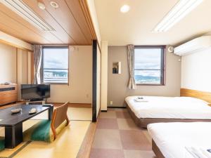 a hotel room with two beds and a tv at Tabist Travel Inn Shinshu Nakano in Nakano