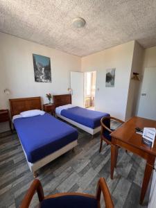 a room with two beds and a desk and a table at Hotel de Champagne in Saint-Dizier