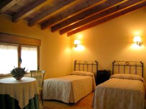 una camera con due letti e un tavolo e una finestra di La Vieja Cantina a Quintana Redonda
