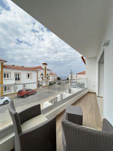 a balcony with two chairs and a view of a street at Alojamento White Rose Boutique in Zambujeira do Mar