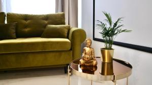 een gouden standbeeld op een tafel in een woonkamer met een bank bij Art Apartments Warszawska 21 Katowice in Katowice