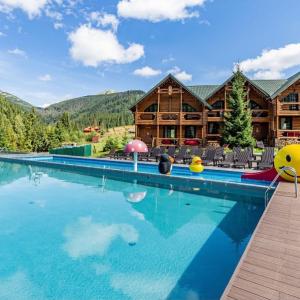 a large swimming pool in front of a log cabin at Красна Поляна Family Club Resorts in Bukovel