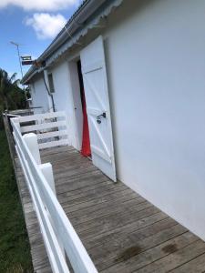Casa blanca con puerta blanca y porche de madera en Domaine De Marly, 3 étoiles, en Sainte-Anne