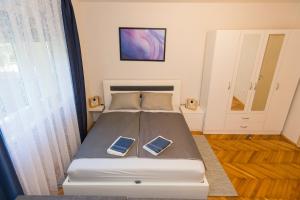 a bed in a room with two cell phones on it at Apartman Studio Blue in Subotica