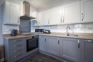 a kitchen with white cabinets and a sink at Brilliant 4 Berth Seaside Apartment In Great Yarmouth, Norfolk Ref 99005s in Great Yarmouth