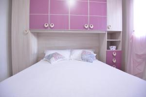 een slaapkamer met een groot wit bed en paarse kasten bij Villa del Sole in Ostuni