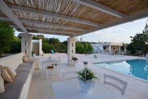 a patio with a couch and tables and a swimming pool at Villa del Sole in Ostuni