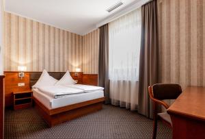 a hotel room with a bed and a desk and a window at Premium Hotel Bacero Wrocław in Wrocław